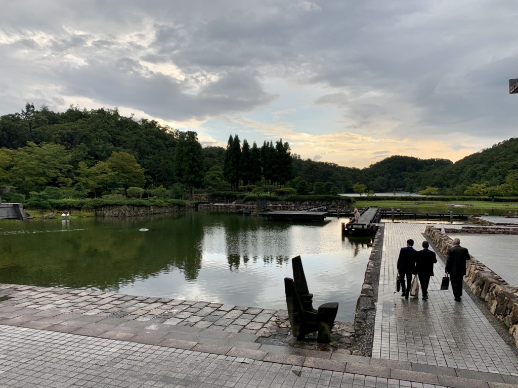 Photograph of a lake with dark clouds clearing and people walking into the distance