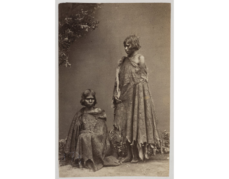 Sepia photographic portrait of two Aboriginal children, one sitting, one standing