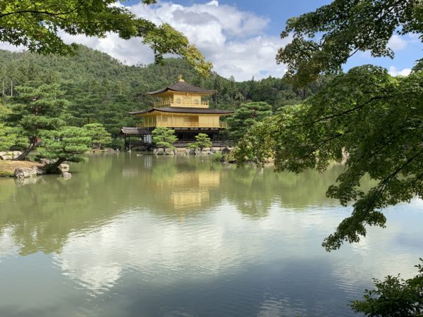 The Golden Pavilion in Kyoto beside a lake with reflections in the water