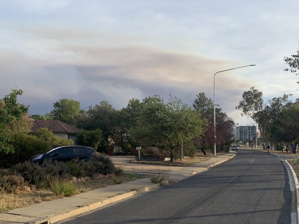 Street scene with a large cloud of bushfire smoke on the horizon