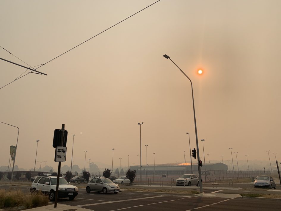 Smoky sky over a street with a hazy orange sun